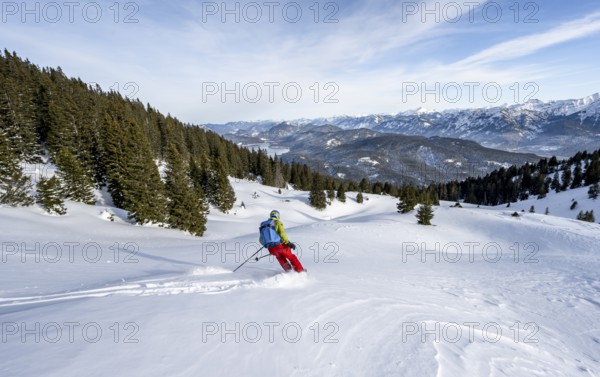 Skiers skiing down the Simetsberg, view of Walchensee and mountain panorama, Estergebirge, Bavarian