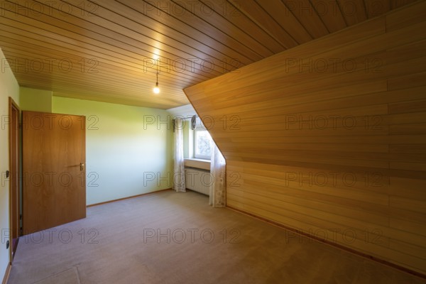 Renovated room in an old building without furniture, brown ceiling panels and wall panels, carpeted