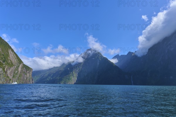 Clear blue waters surrounded by high mountains and clouds, summer, Milford Sound, Te Anau,