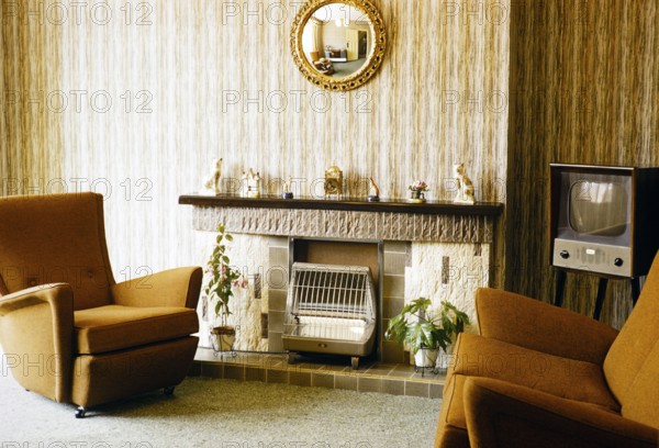 Living room with television, electric fireplace and armchairs, England, photographed in 1962