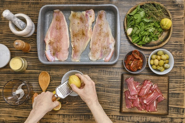 Hands rub the zest of lemon for sauce to cook juicy fish