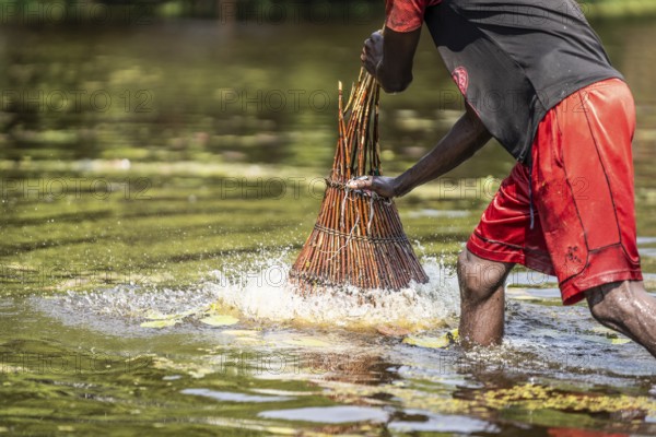 Fisherman pushing a basket into the shallow river for catching fish with his basket. Kalabo,