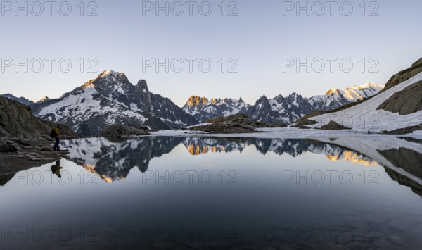 Tourist at a mountain lake in the morning, mountain landscape at sunrise, water reflection in Lac