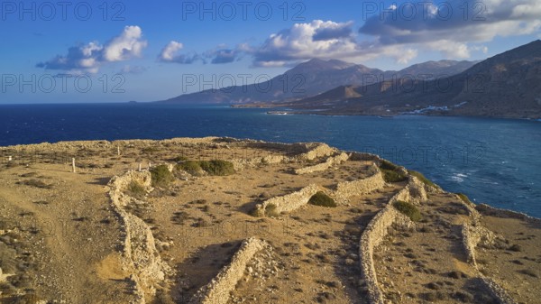 Drone shot, Archaeological excavation site, landscape of ruins by the sea with distant view of