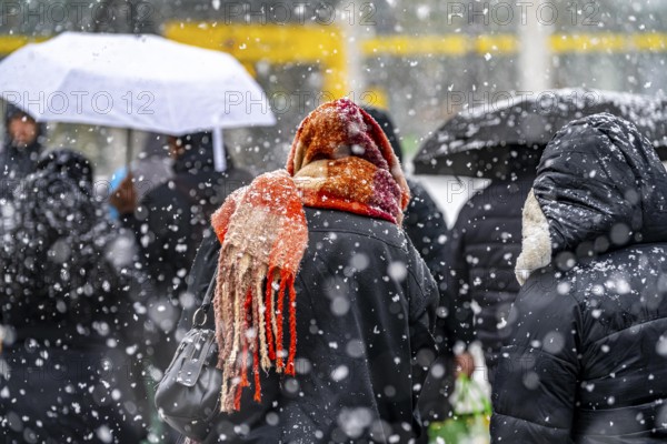 Winter weather, heavy snowfall, city centre traffic, passers-by in the snow, person with thick