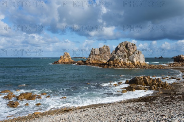 Steep rock formations on the coast with crashing waves and a cloudy blue sky, Plage de Pors Scaff,