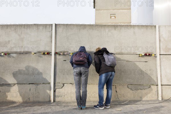 Two visitors look through a gap in the Wall at the central commemorative event at the Berlin Wall