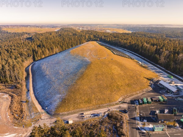 Panoramic view of a grassy hill and neighbouring forests, partly snow-covered, landfill, Neubulach,