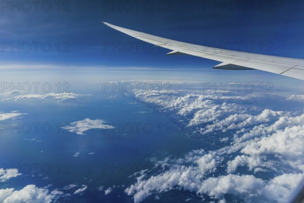 Above the clouds over the Indian Ocean. On the left, the coast of India. View from the aircraft