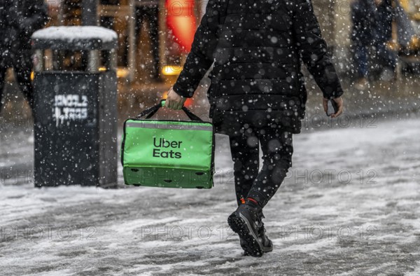 Winter weather, heavy snowfall, city centre traffic, courier of the delivery service Uber East, on