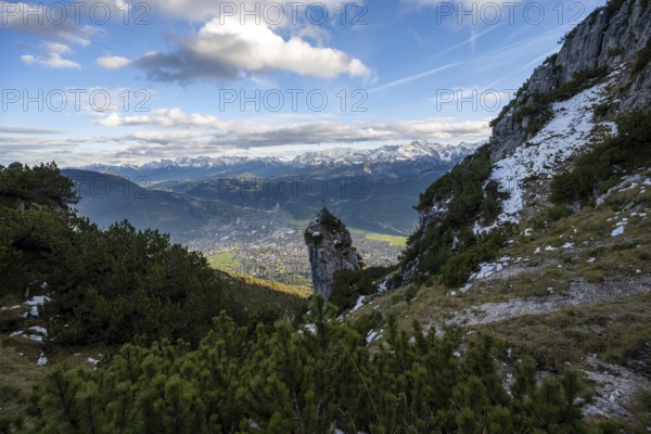Rocky peak with summit cross, view of Garmisch-Partenkirchen and mountain panorama, hike to