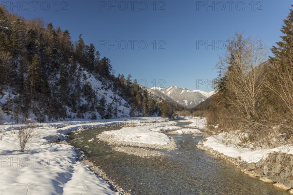 The Riss creek flowing through a snow covered landscape in the Eng valley. Sunny day with blue sky