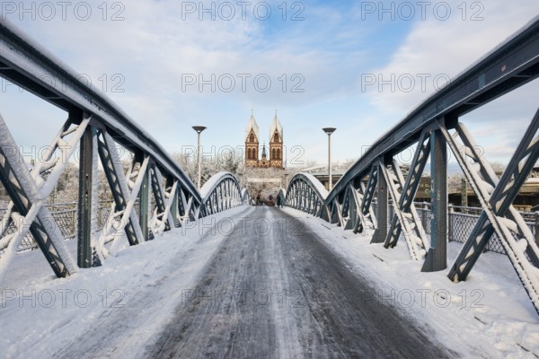 Bridge with snow and ice and cyclists, Blue Bridge and Stühlinger Church, Freiburg im Breisgau,