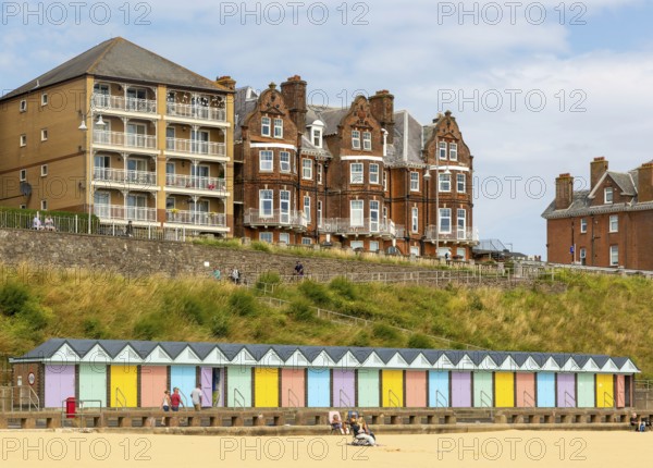 Colourful beach huts and historic clifftop buildings, South Beach, Lowestoft, Suffolk, England, UK