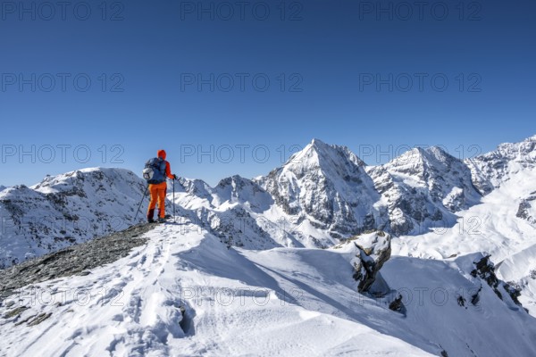 Ski tourers on foot, snow-covered mountain landscape in winter, view of mountain peaks