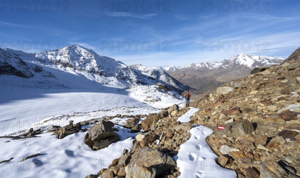 Mountaineer on a hiking trail with snow, descent from Ramoljoch at Spiegelferner, autumnal mountain