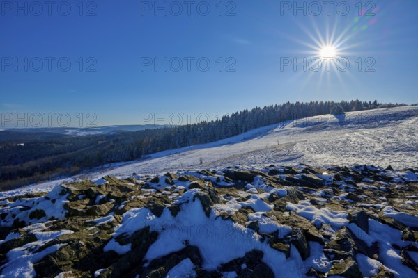 Snow-covered landscape under the bright sun, surrounded by rocks and forests, Abtsroderkuppe,