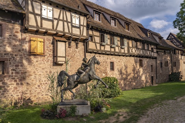 Statue of a woman on horseback with horse La Dame du Parc by the artist Josepha and half-timbered