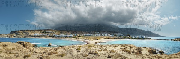 A wide panorama at Frangolimiona sandy beach with mountains and clouds under a blue sky, Arkasa,