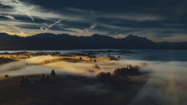 Autumn sunrise in the foothills of the Alps with fog at Illasbergsee and Forggensee near Halblech