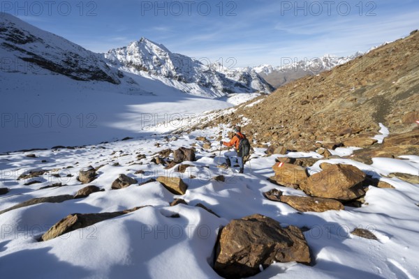 Mountaineer on a hiking trail with snow, descent from Ramoljoch at Spiegelferner, autumnal mountain