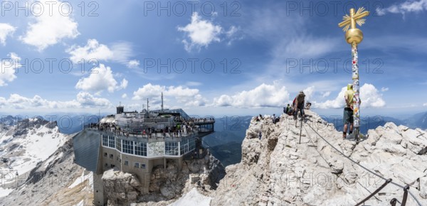 Summit of the Zugspitze with golden summit cross and modern mountain station of the Bavarian