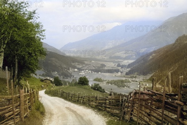 Country road lane leading to villages rural settlement in Alpine mountain valley Tyrol, Austria,