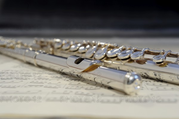 Transverse flute lying on a sheet of music, musical instrument in silver