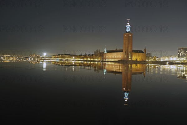 Illuminated building reflected in calm water at night, with a clear dark sky, capital city, city
