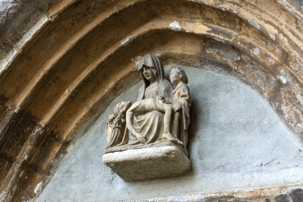 Sculpture of Pieta is prominently displayed above the portal of the church in Collanges, Puy de
