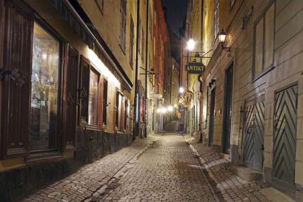 Narrow, illuminated cobblestone alley at night with old charming buildings, winter, Gamla Stan, Old
