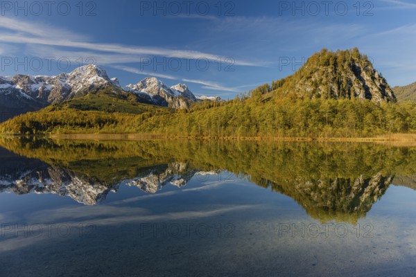 Lake Almsee in autumn with mountains reflected in the lake. Blue sky