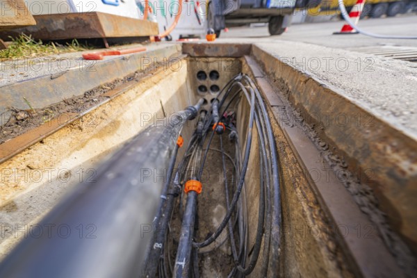 Open manhole with numerous cables and pipes at a construction site, Wend Glasfasermontage