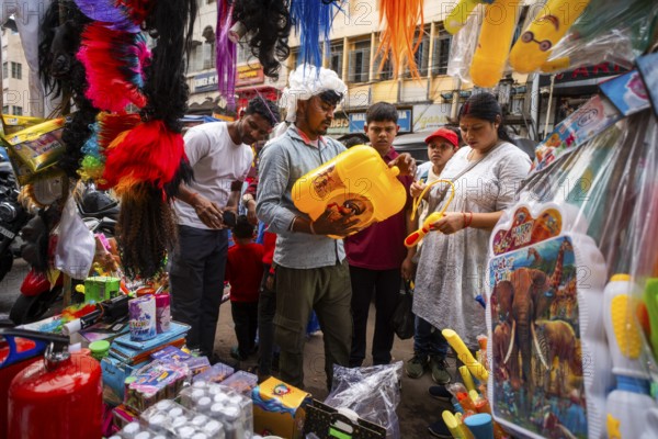 People buy Holi celebration items in a market on the eve of Holi Festival, on March 13, 2025 in