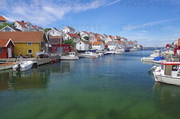 Colourful houses on the water with several boats, under a sunny sky, idyll, crystal clear water,