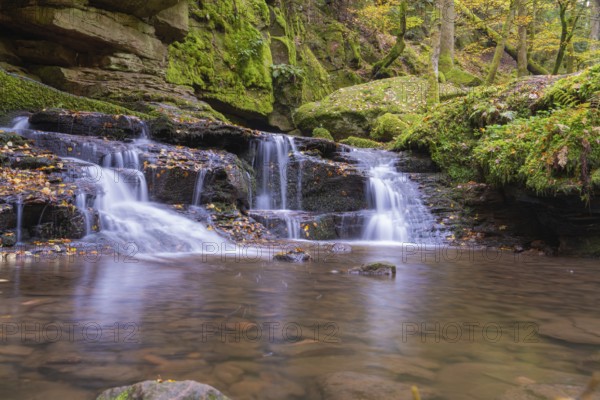 Small waterfall in a moss-covered forest with autumn leaves, Monbachtal, Bad Liebenzell, district