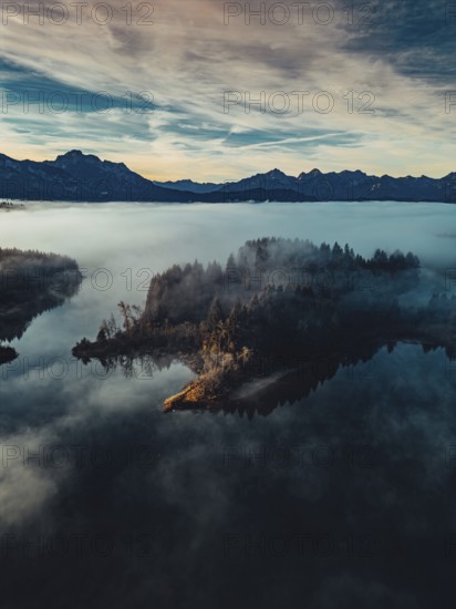 Autumn sunrise in the foothills of the Alps with fog at Illasbergsee and Forggensee near Halblech
