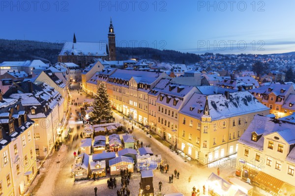 The snow-covered Christmas market with St Wolfgang's church seen from the town hall tower,
