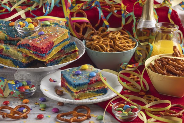 Colourful cakes and pretzels alongside drinks and party decorations, carnival