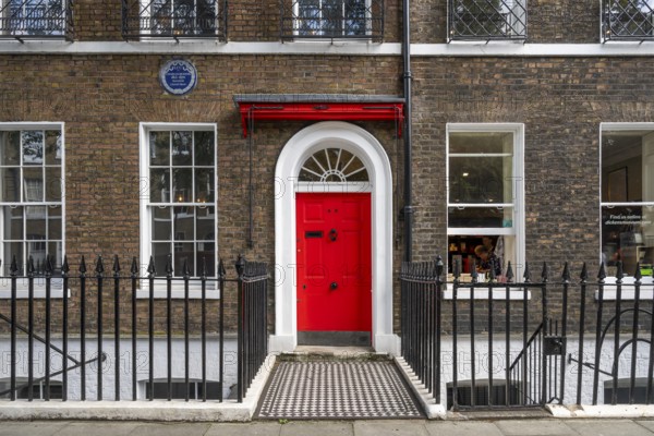 Red entrance door in a brick building with a cast-iron fence, Charles Dickens Museum, 48-49 Doughty