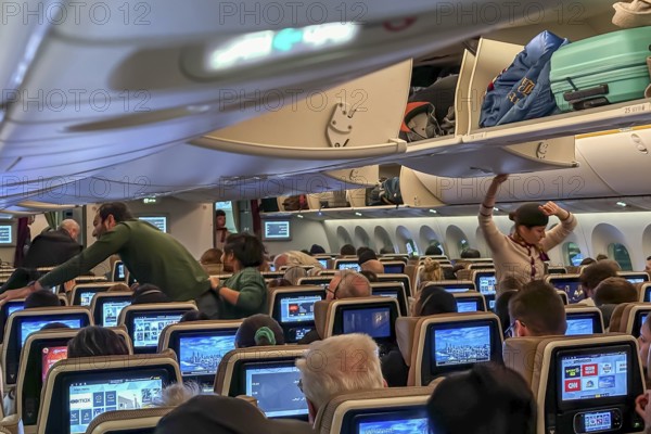 Etihad airline aircraft, interior, rows of seats with passengers. Boeing 787 aircraft on a flight