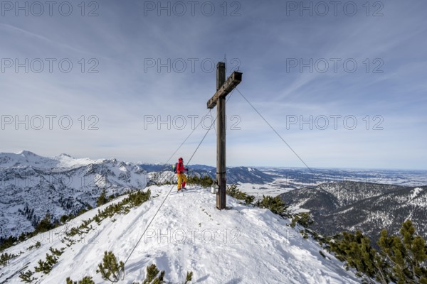 Ski tourer at the summit of the Simetsberg with summit cross, mountain panorama, Estergebirge,