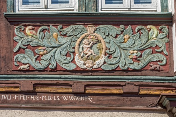 Colourfully painted carvings, medallion with putti, paradise, floral ornaments, half-timbered house