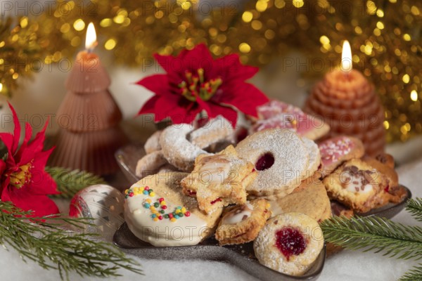 A plate full of biscuits surrounded by candles and red poinsettias