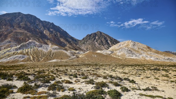 Vast desert-like landscape with volcanic rock and mountain range under a clear sky, volcanism,