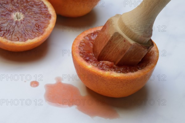 Halved blood orange with citrus squeezer, orange