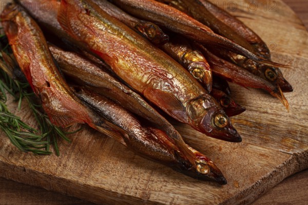 Cold smoked capelin, on a wooden chopping board, no people
