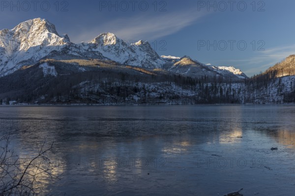 Lake Almsee in winter. Snow on the mountains and a clear blue sky. Perfect reflection on the lake