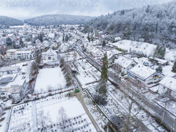 Snow-covered landscape of a village with houses, trees and a cemetery in winter, Aidlingen,