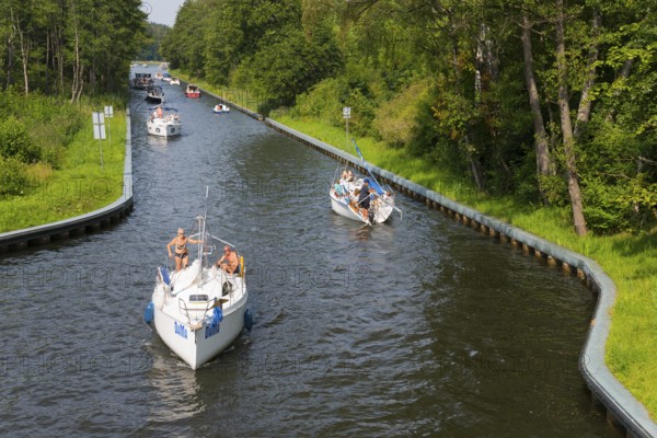 Boats glide along a tree-lined canal surrounded by summer nature, Gizycko, Warminsko-Mazurskie,